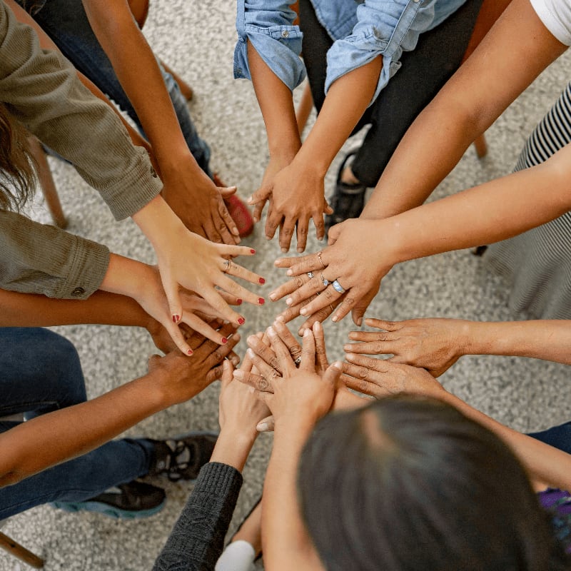 A group of people standing in a circle with their hands together