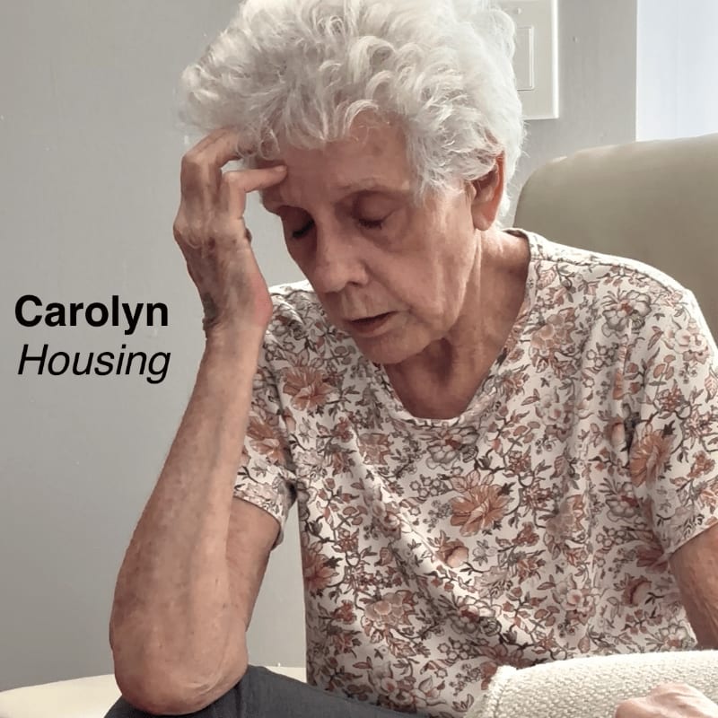 An elderly woman with gray hair rests her head on her hand in the foreground, while the background is a blurred interior with text on the left.