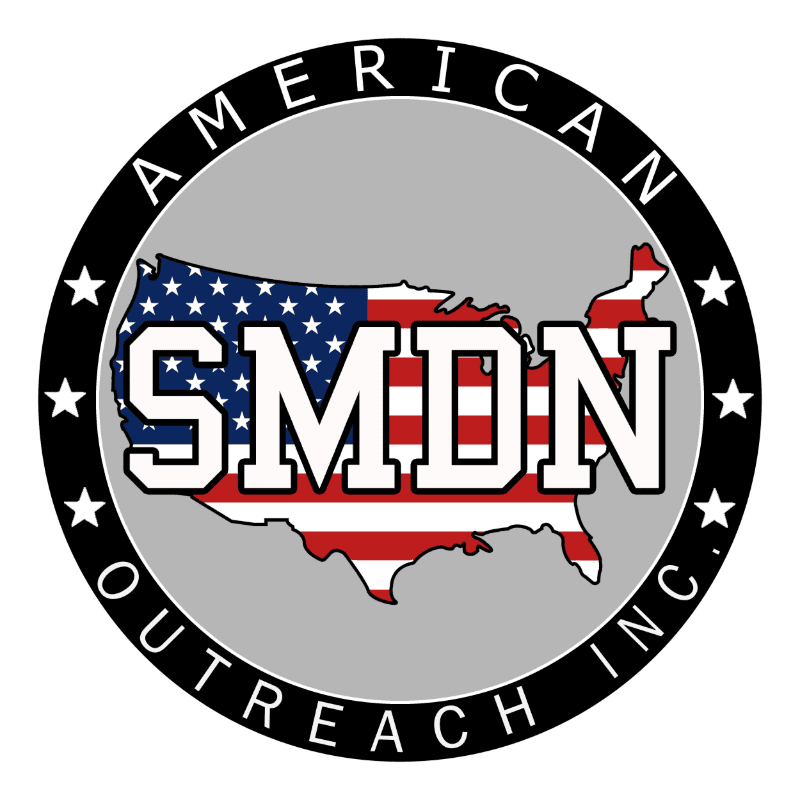 A circular logo with the American flag superimposed with the letters "SMDN" in the foreground, and the words "AMERICAN OUTREACH INC." encircling the flag in the background.