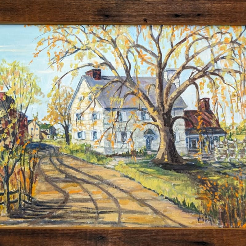 A winding dirt road leads past a large, old tree with yellowing leaves towards a stone house with a red roof, set against a bright blue sky.
