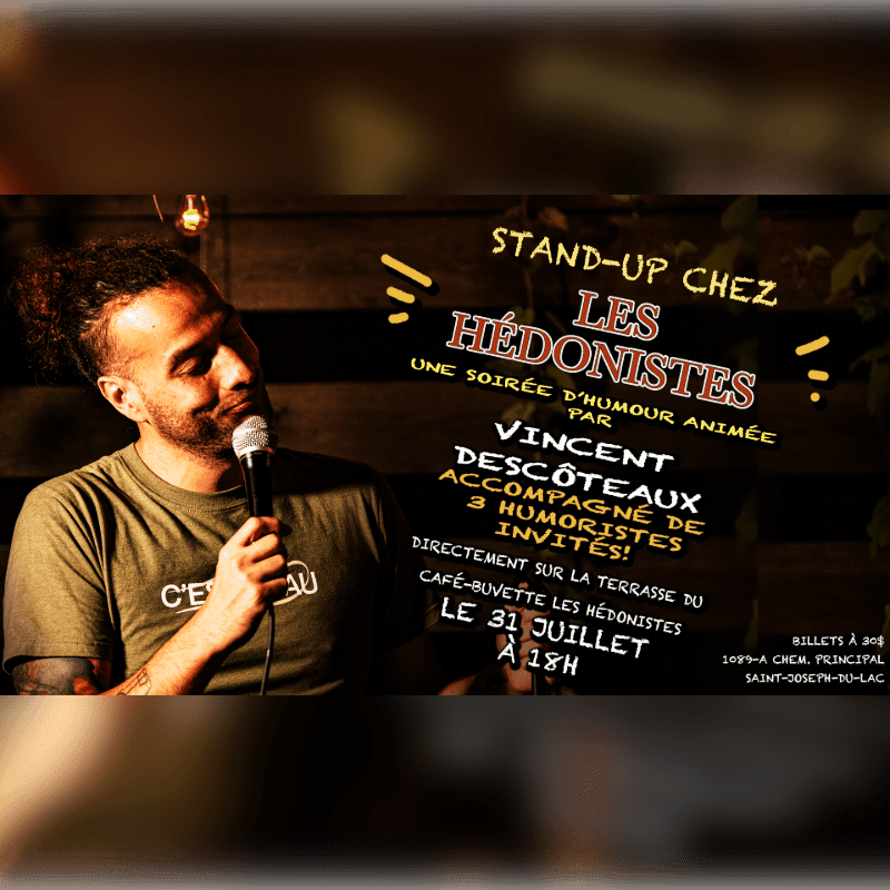 A man with a microphone stands on a terrace in front of a poster advertising a comedy show.