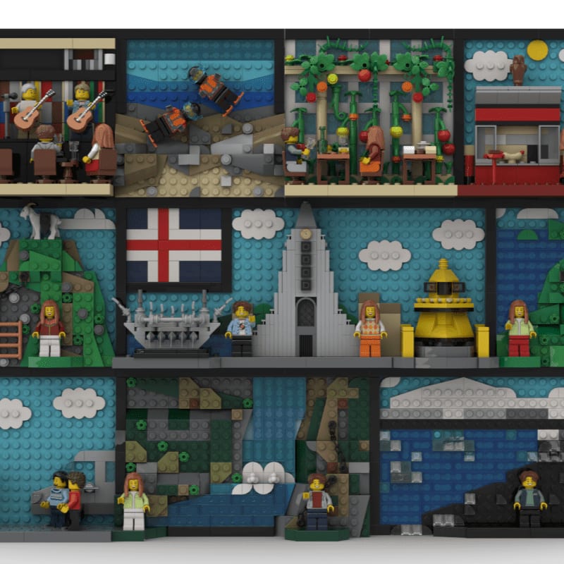 A Lego diorama displays various scenes, from a band playing in a cafe to a lighthouse and a waterfall, all set against a backdrop of blue skies and clouds.