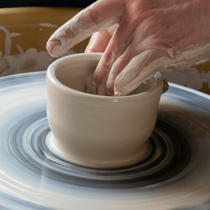 person making clay pot on white round plate