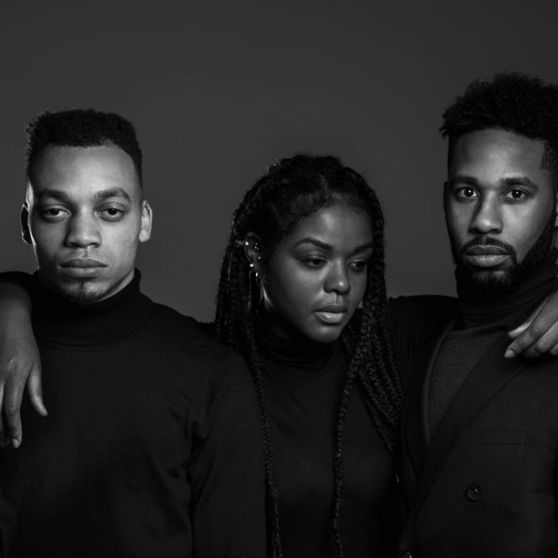grayscale photo of woman standing between two men