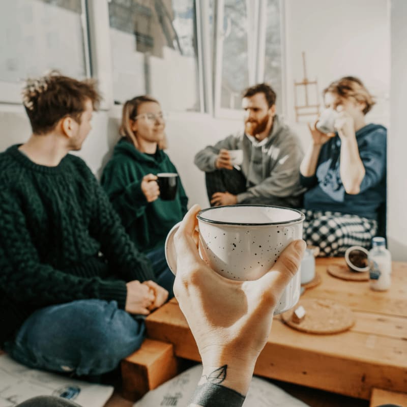 people sitting on chair holding white ceramic mug
