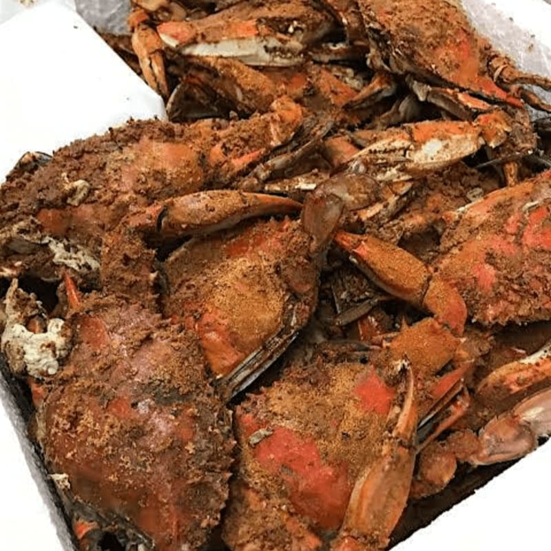 A close-up view of a pile of seasoned crabs in a white box.