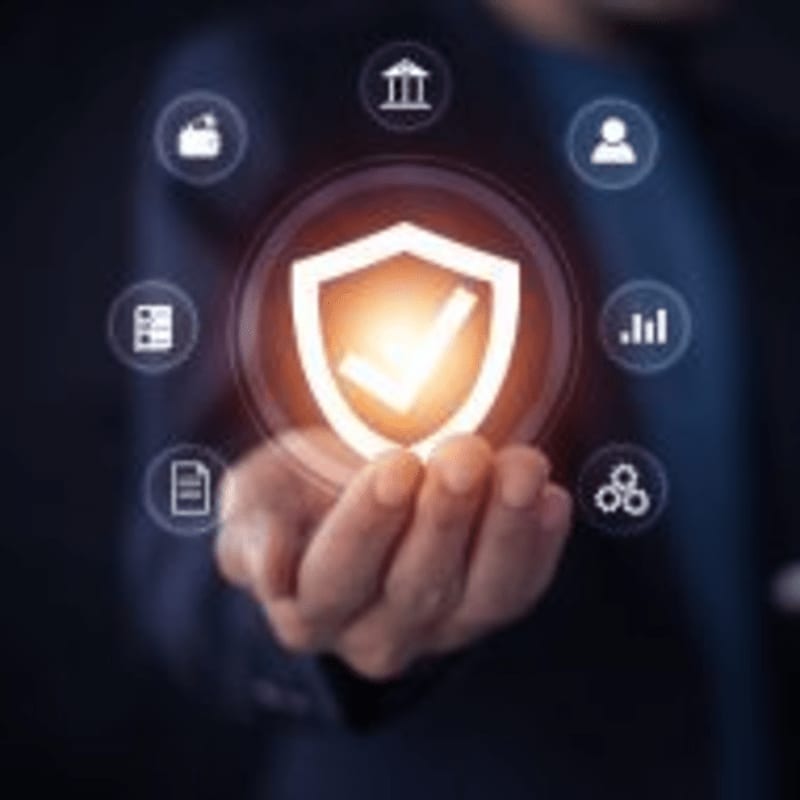 A hand holds a glowing shield with a checkmark, surrounded by digital icons representing various services against a dark, blurred background.