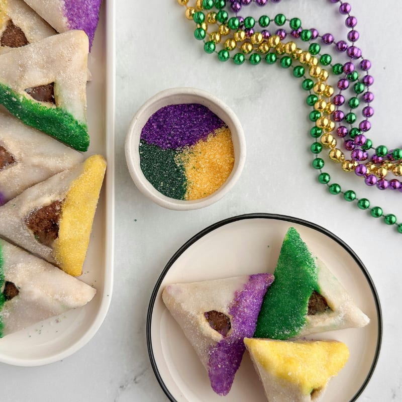 Triangular cookies decorated with purple, green, and yellow sugar