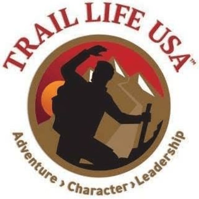 A silhouette of a hiker with a backpack and ice axe is centered in a circular emblem with mountains and a setting sun in the background, all surrounded by the words "TRAIL LIFE USA" and "Adventure Character Leadership."