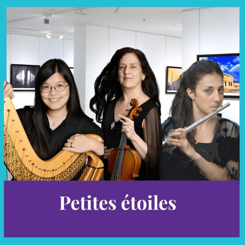 Three women, one playing a harp, one holding a violin, and one playing a flute, pose in front of artwork in a gallery.