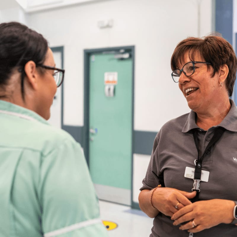 a woman talking to another woman in a hospital hallway