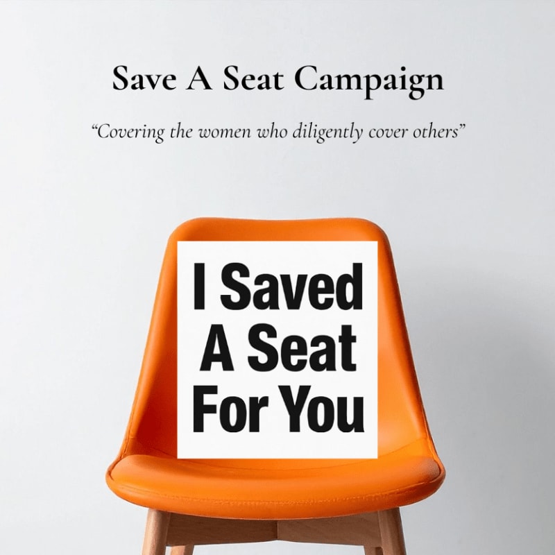 An orange chair in the foreground displays a white sign that reads "I Saved A Seat For You," set against a plain white background with campaign text above.