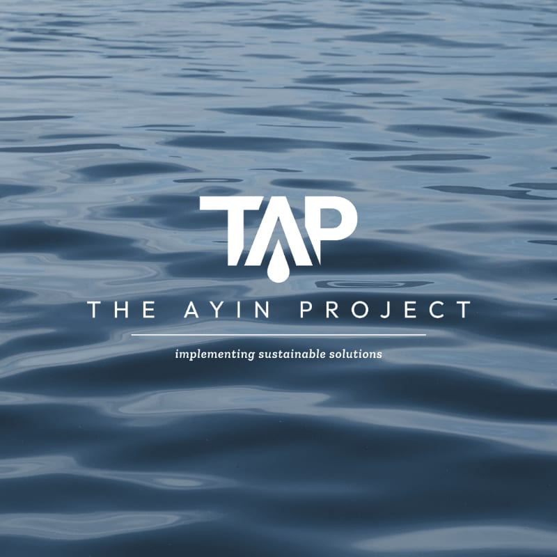 Rippling blue water fills the background, with the white "TAP THE AYIN PROJECT" logo and tagline "implementing sustainable solutions" centered in the foreground.