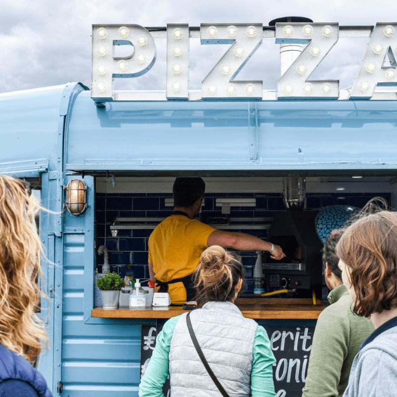 a group of people stand outside a food truck