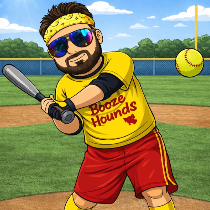 A man in a yellow shirt and red shorts, wearing a bandana and sunglasses, swings a baseball bat on a field with a softball in the air.