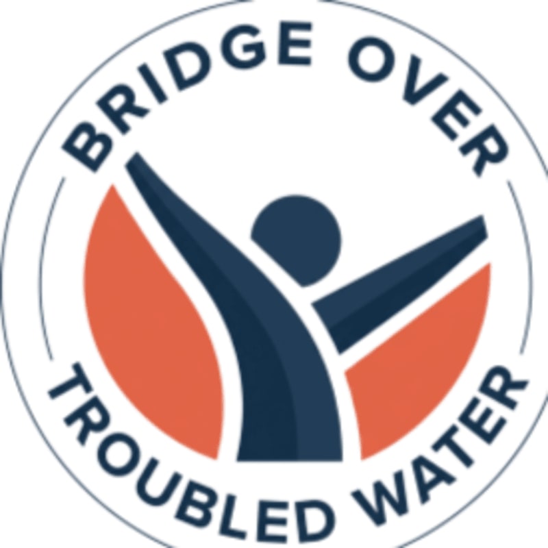 A circular logo with the words "BRIDGE OVER TROUBLED WATER" encircling a stylized figure with outstretched arms against an orange background.