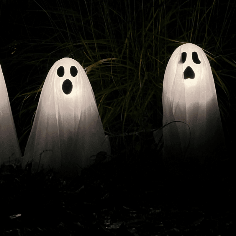 three ghost statues in the dark with their faces glowing
