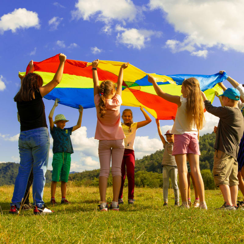 children playing with colorful parachute on grass