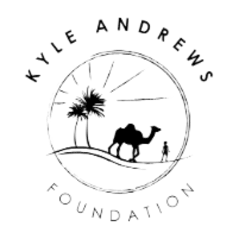 A black and white logo features a camel and a small figure walking through a desert landscape with palm trees under a sunburst, all enclosed within a circular outline, with "KYLE ANDREWS FOUNDATION" written above and below.