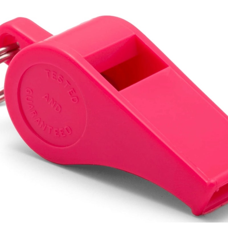 A bright pink plastic whistle rests on a white surface, with a blurred white background.