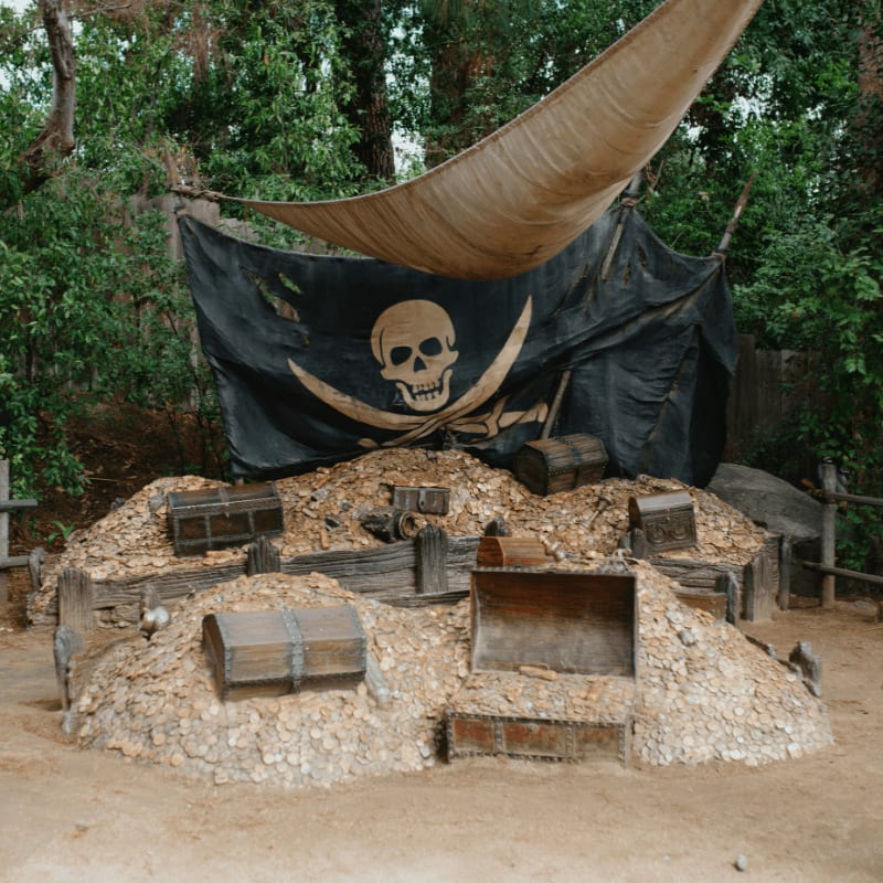 Pirate flag and treasure chests on a pile of hay.