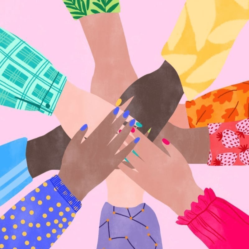 A circle of diverse hands with colorful sleeves and painted nails are stacked in the foreground against a soft pink background.