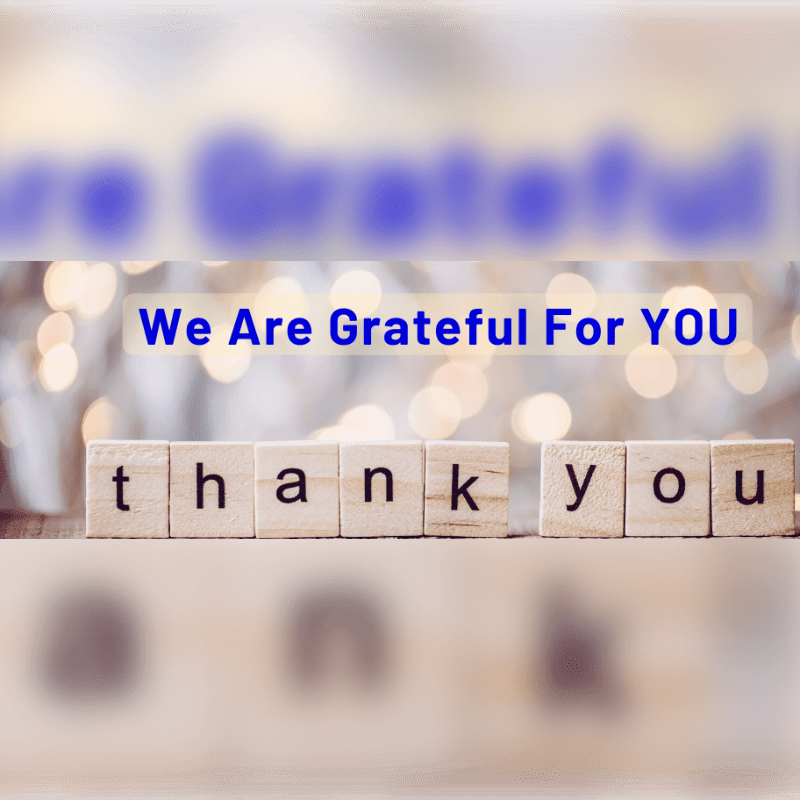Wooden blocks spelling "thank you" are in the foreground, with a blurred background of bokeh lights and the words "We Are Grateful For YOU" in blue text.