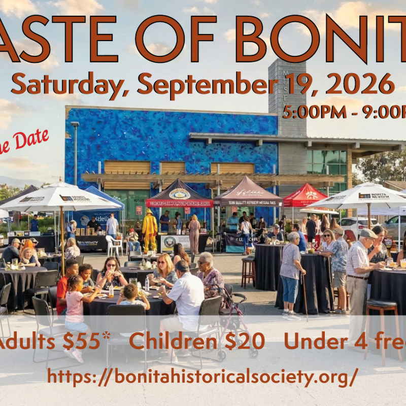 People gather at tables under tents in front of a blue building for a "Taste of Bonita" event.