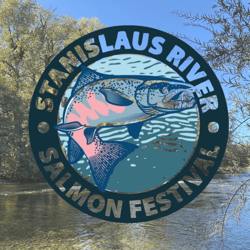 A circular logo featuring a salmon and the text "STANISLAUS RIVER SALMON FESTIVAL" is superimposed over a blurred background of a river and trees under a clear blue sky.