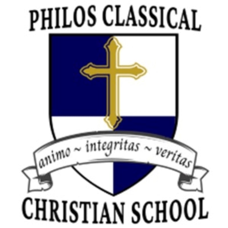 A shield with a gold cross on a blue and white background is centered in the foreground, with the words "PHILOS CLASSICAL" above and "CHRISTIAN SCHOOL" below, all on a white background.
