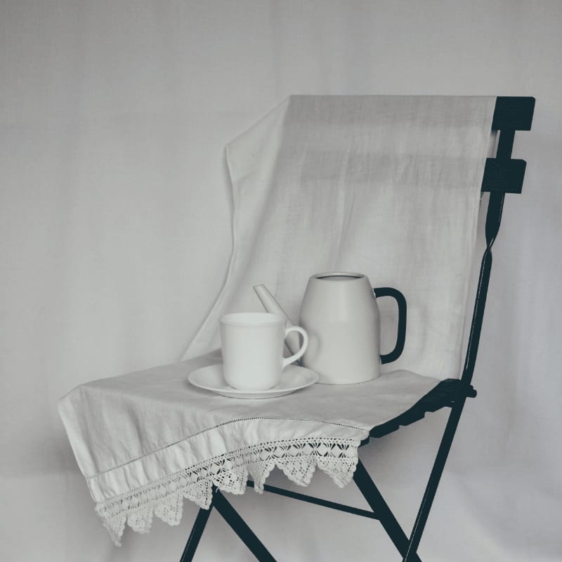a white table with a white cloth and a white teapot on it