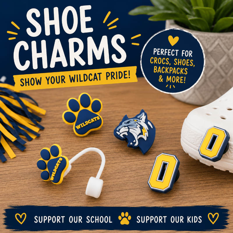 Five "Wildcats" themed shoe charms, including paw prints and a wildcat head, are displayed on a wooden surface in the foreground, with a white shoe and a green plant visible in the background.