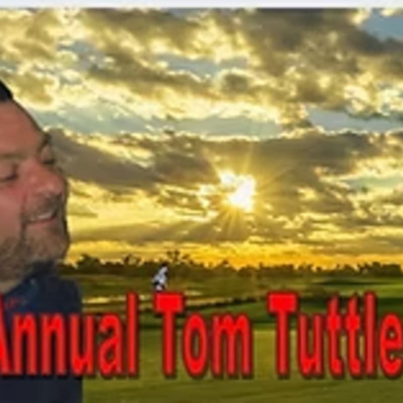 A man smiles in the foreground with a golf course and a sunset in the background.