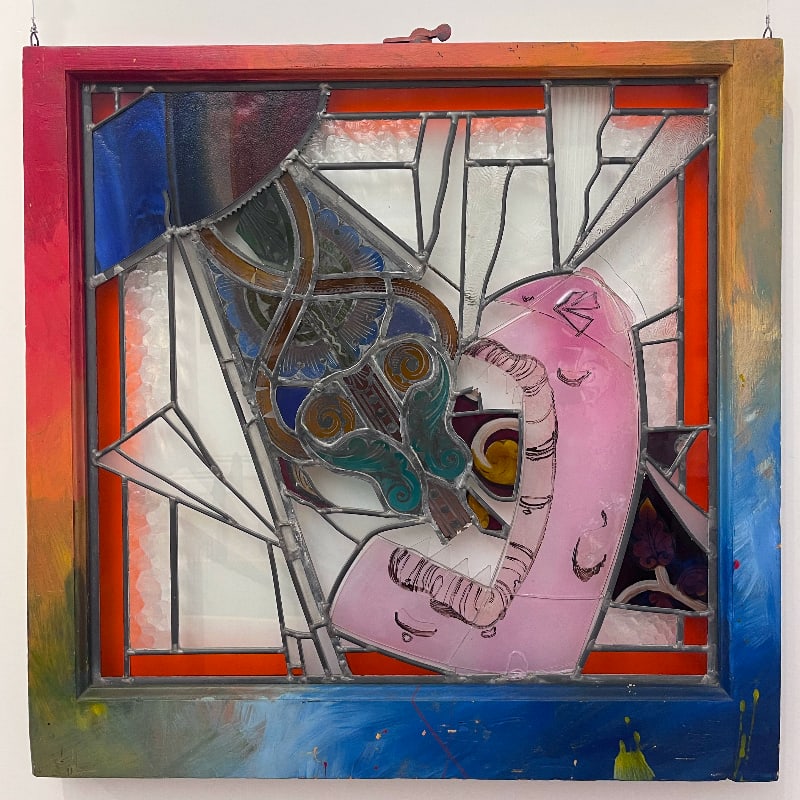 A stained glass artwork featuring a pink figure embracing a guitar is framed by a colorful, painted wooden border.