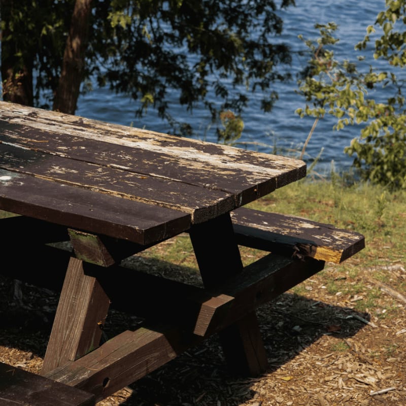 a wooden picnic table sitting next to a body of water