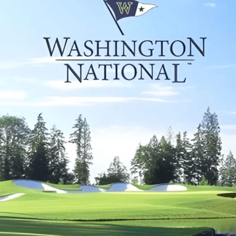 A pristine golf course with manicured greens and sand traps is set against a backdrop of tall evergreen trees and a bright blue sky with a flag bearing the "W" logo.