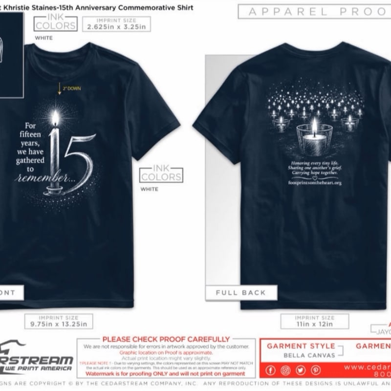 A dark blue t-shirt with a lit candle and the number 15 on the front, and a group of lit candles with text on the back, is displayed against a white background.