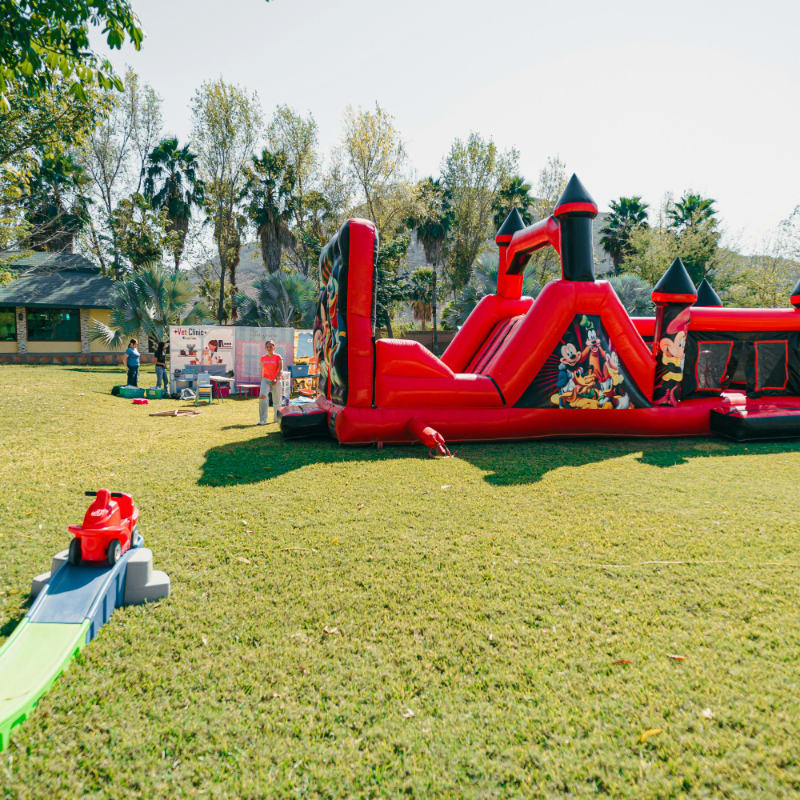 A red inflatable castle bounce house on a grassy lawn.