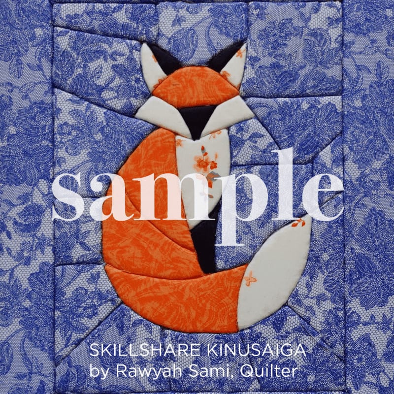 A quilted fox with an orange, white, and black body sits against a blue floral background.