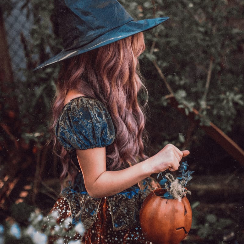 woman in black hat and brown dress holding pumpkin