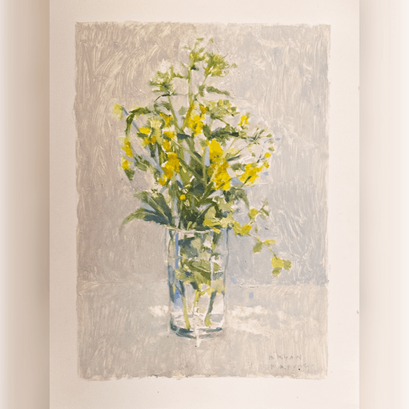 A glass vase filled with yellow wildflowers sits on a table against a textured, light gray background.