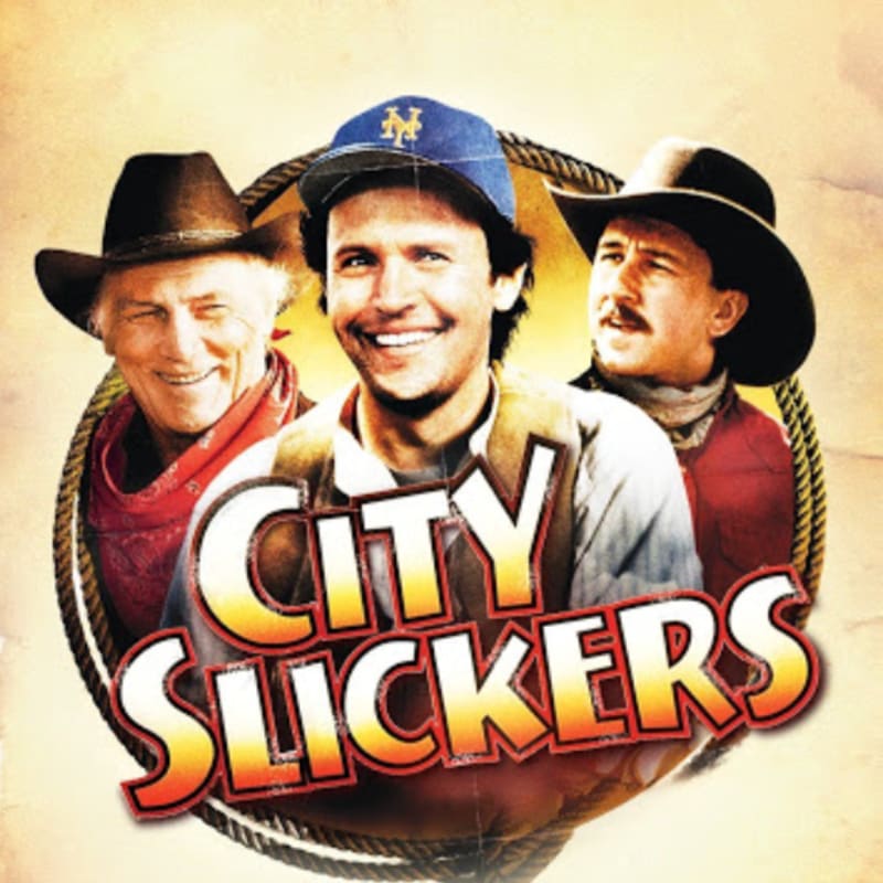Three smiling men in cowboy hats and western attire are featured in the foreground, with the "City Slickers" title superimposed, against a textured, sepia-toned background.