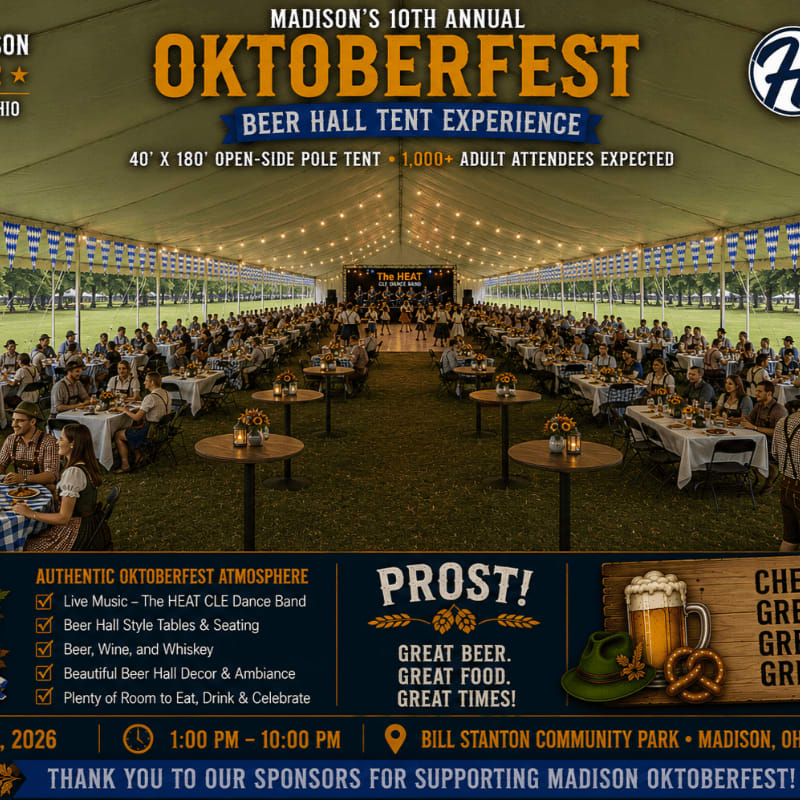 A long, open-sided tent filled with tables and people enjoying Oktoberfest festivities is set up in a park.