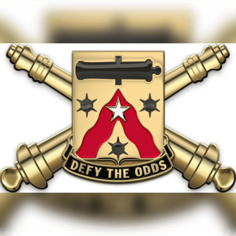 Two golden cannons are crossed behind a shield with a white star and red chevron, all set against a blurred white and gold background.