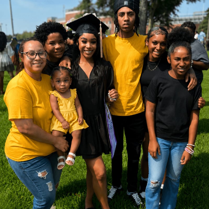 A family poses for a photo on a grassy field with a building in the background.