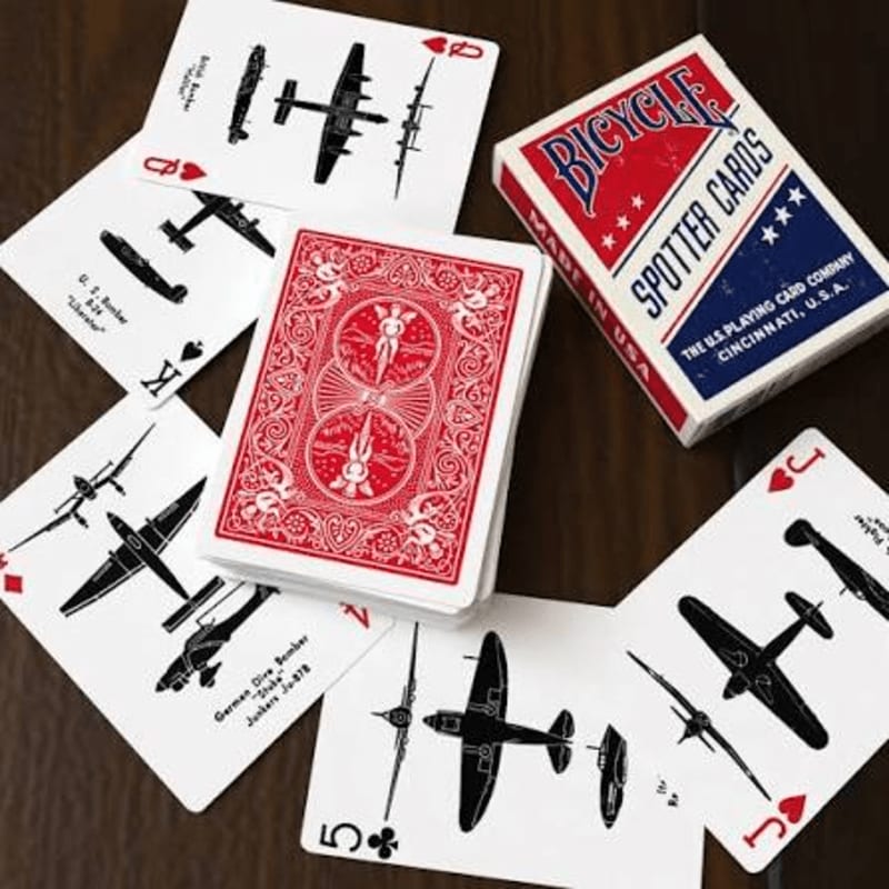 A deck of Bicycle Spotter Cards featuring vintage aircraft is spread out on a wooden surface, with the red-backed cards in the center.