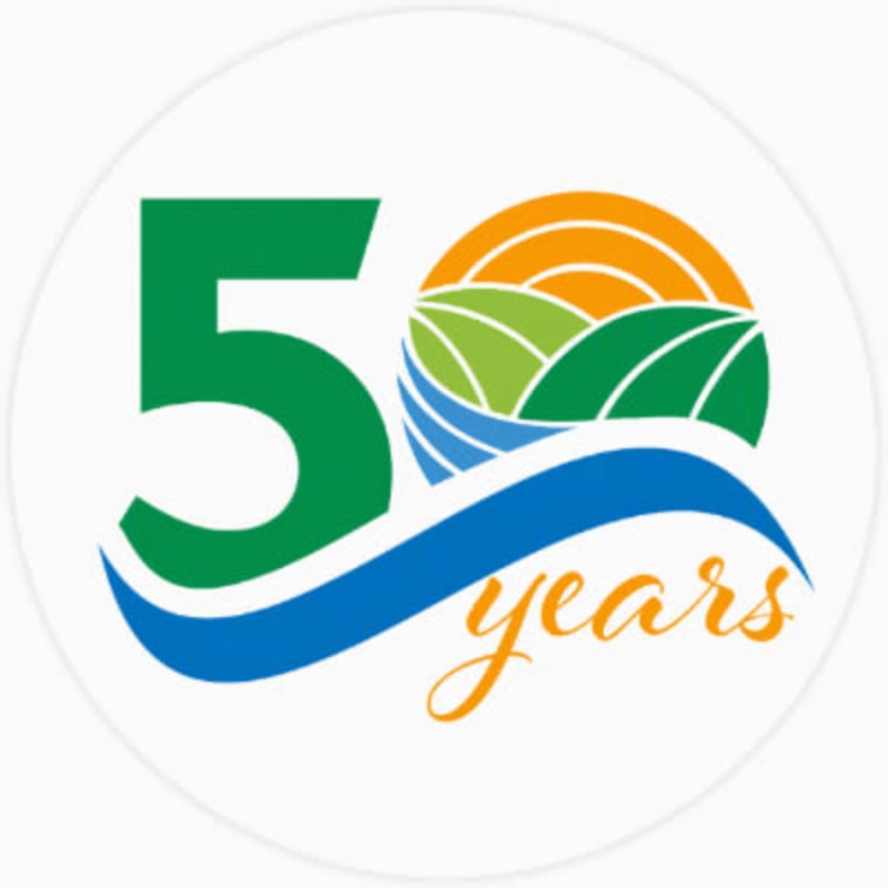 A large green "5" is in the foreground, with a blue wave curving around it and the word "years" in orange script, while the background features rolling green hills under an orange sun.