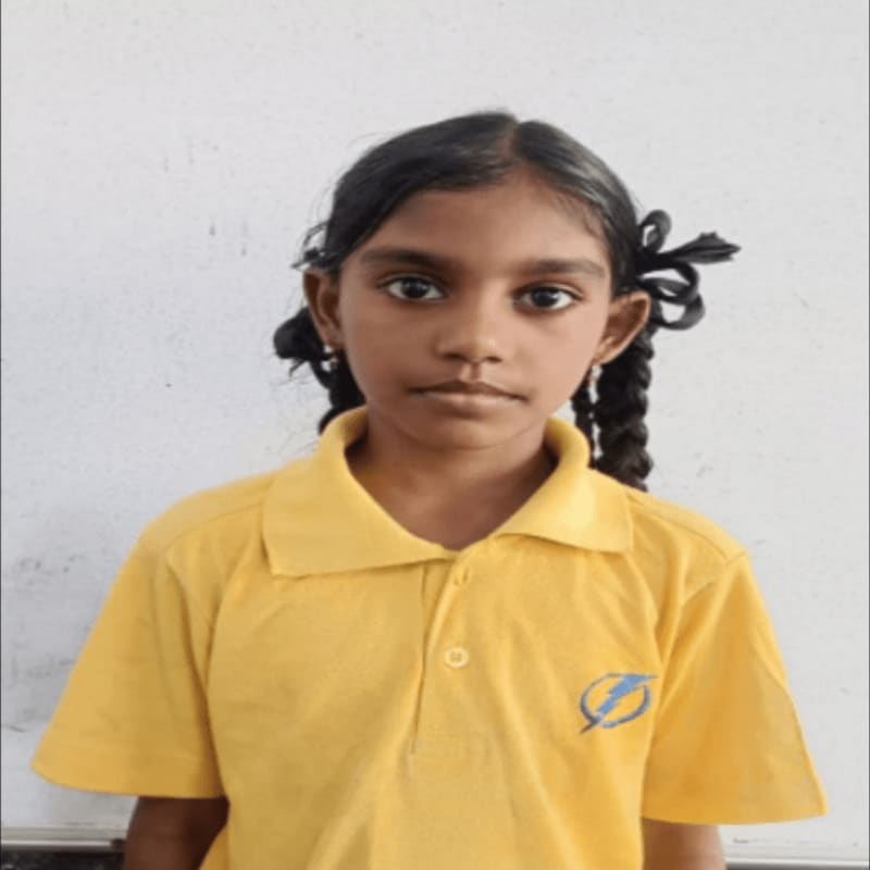 A young girl with dark hair in braids, wearing a yellow polo shirt, stands against a plain white background.