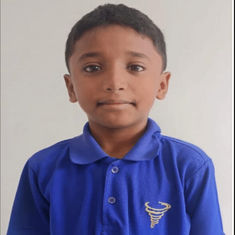A young boy in a blue shirt stands against a plain white background.