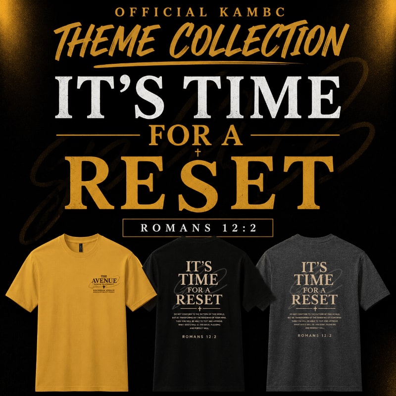 Three t-shirts, one yellow and two dark-colored, are displayed against a black background with golden text that reads "OFFICIAL KAMBC THEME COLLECTION IT'S TIME FOR A RESET ROMANS 12:2".
